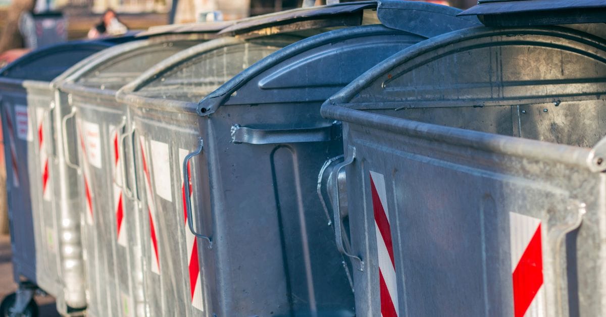 Row of galvanized metal recycling bins with red and white safety stripes