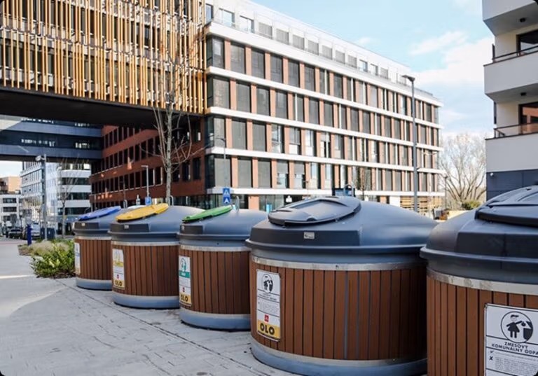 Modern waste bins with colored lids for recycling in an urban environment.