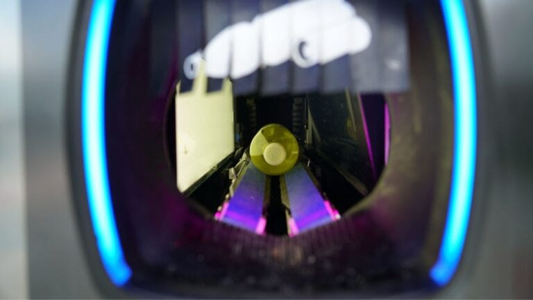 A plastic bottle inside a recycling machine, about to be processed.