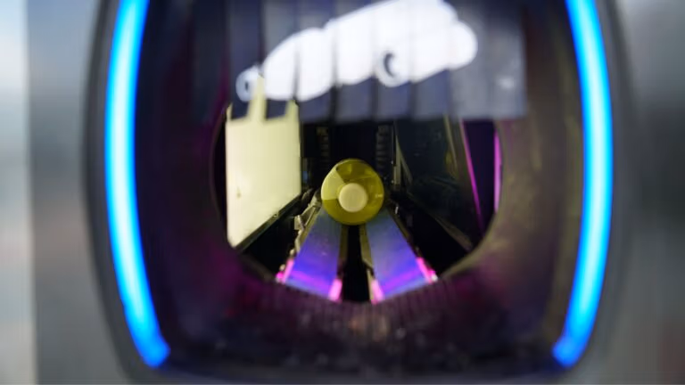 A plastic bottle inside a recycling machine, about to be processed.