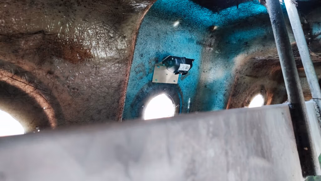  Interior of a container with a sensor mounted on the wall, used for monitoring waste levels or conditions inside the container.