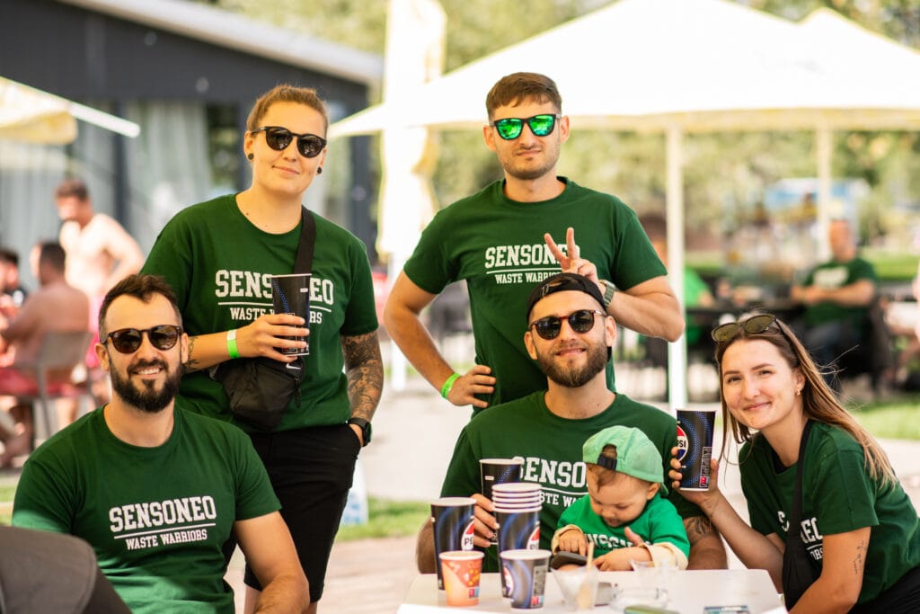 Group of Sensoneo employees wearing matching “Waste Warriors” shirts, smiling together at an outdoor event.
