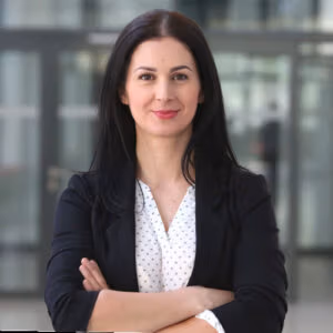 Woman with long dark hair in a blazer, smiling.
