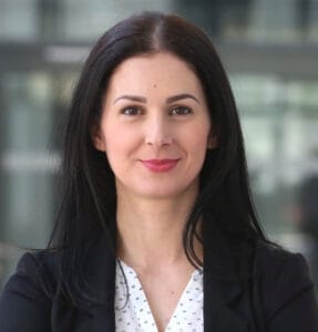 Woman with long dark hair in a blazer, smiling.