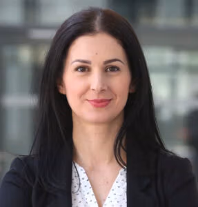 Woman with long dark hair in a blazer, smiling.