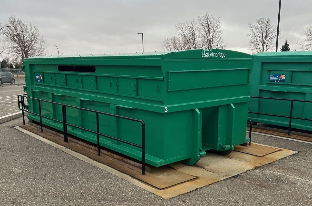 A large outdoor recycling or waste container secured on a concrete pad, designed for organized and efficient waste collection.