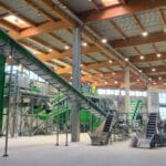 Large indoor recycling facility with multiple conveyor systems and sorting equipment.
