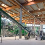 Large indoor recycling facility with multiple conveyor systems and sorting equipment.