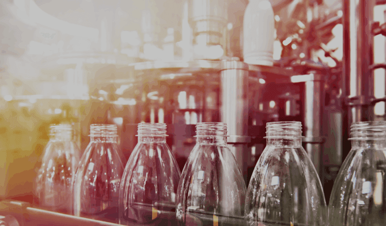 Row of empty plastic bottles on an automated production line.
