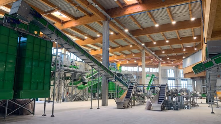 Large indoor recycling facility with multiple conveyor systems and sorting equipment.
