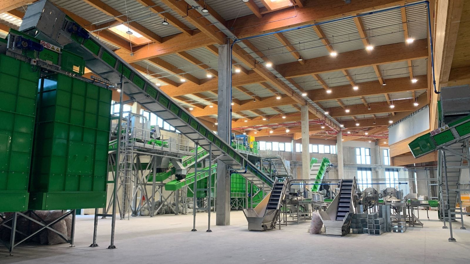 Large indoor recycling facility with multiple conveyor systems and sorting equipment.
