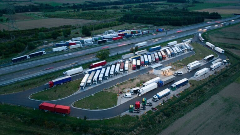 Aerial view of a busy truck parking and rest area near a highway.
