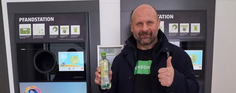 Sensoneo CEO smiles while returning a bottle at a recycling station.