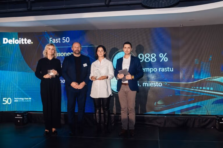 Four people stand stage holding an award for the top 50 fastest growing technological companies.