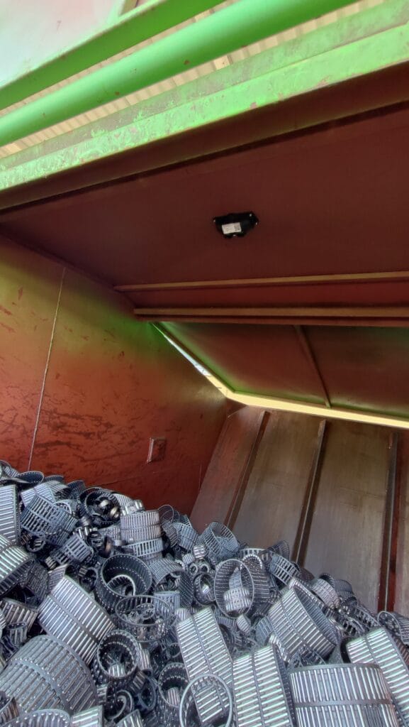 Sensor mounted inside a waste container above a pile of metal scrap.