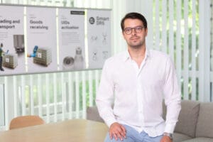 Man in glasses wearing a white shirt, looking at the camera with a neutral expression.