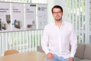 Man in glasses wearing a white shirt, looking at the camera with a neutral expression.

