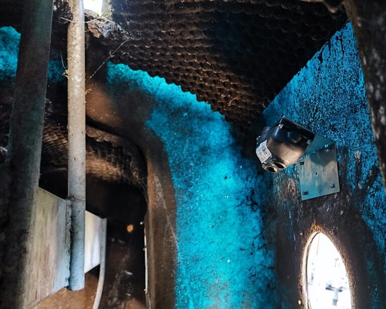 A mounted sensor is installed inside an industrial container with textured walls.