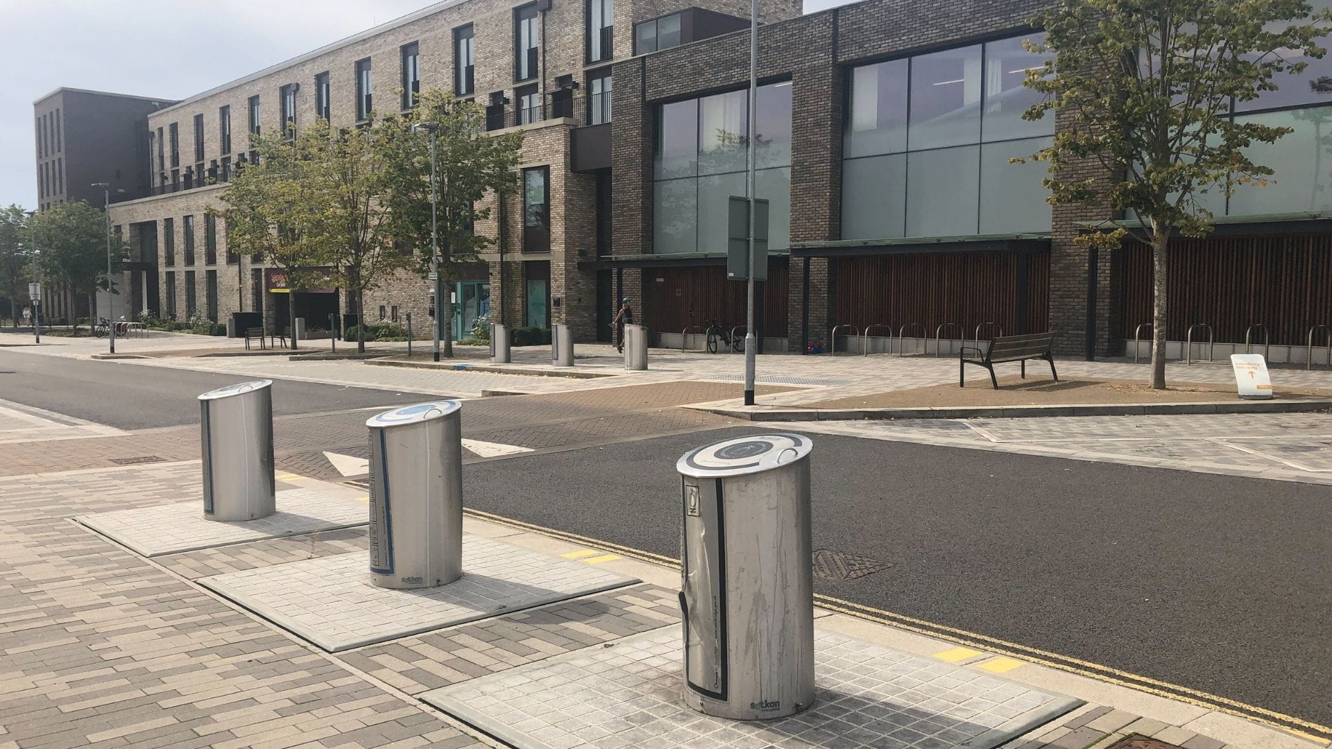 Street with modern semi-underground waste bins installed along the sidewalk.
