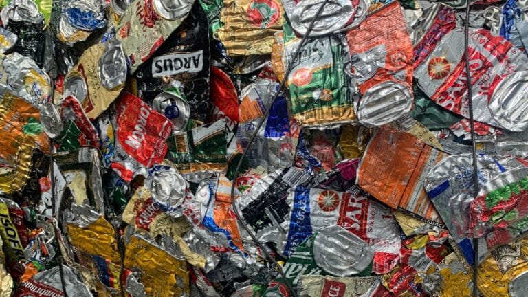 A tight stack of crushed aluminum cans compressed into a recycling bale.