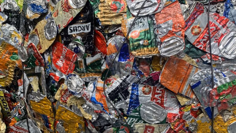 A tight stack of crushed aluminum cans compressed into a recycling bale.
