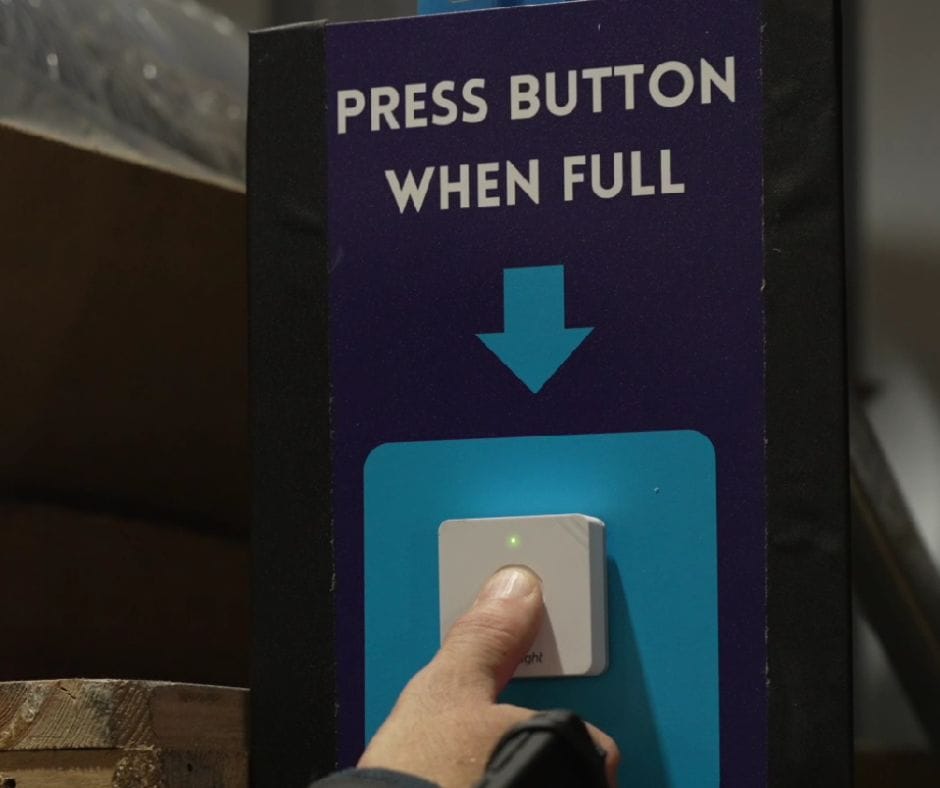 Person pressing a notification button indicating a bin is full.
