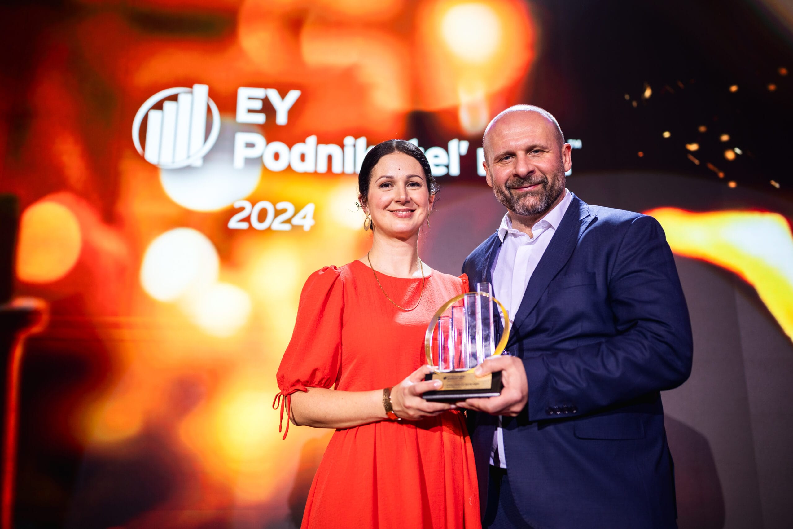 The Sensoneo co-founders on stage holding an award at an EY 2024 event.