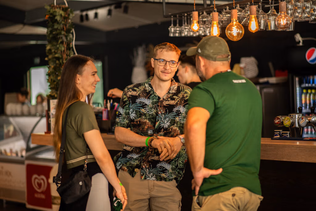 Three people casually talking at a bar counter.