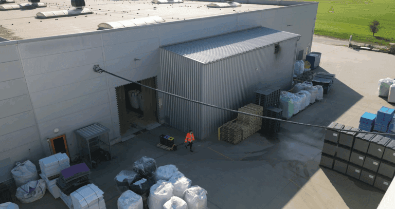 Factory yard with stacked pallets and sorted waste bags.