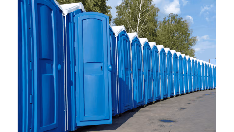 Row of blue portable toilets lined up outdoors.
