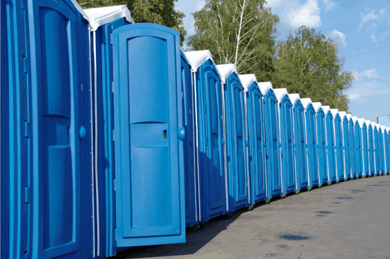 Row of blue portable toilets lined up outdoors.