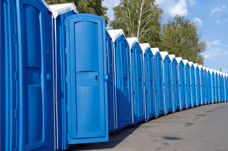 Row of blue portable toilets lined up outdoors.