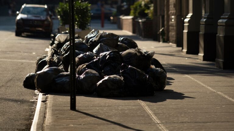 A pile of black garbage bags overflowing, showing unmanaged urban waste.