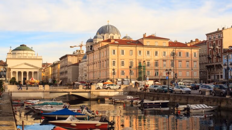 Waterfront city with historic buildings, boats and street activity.