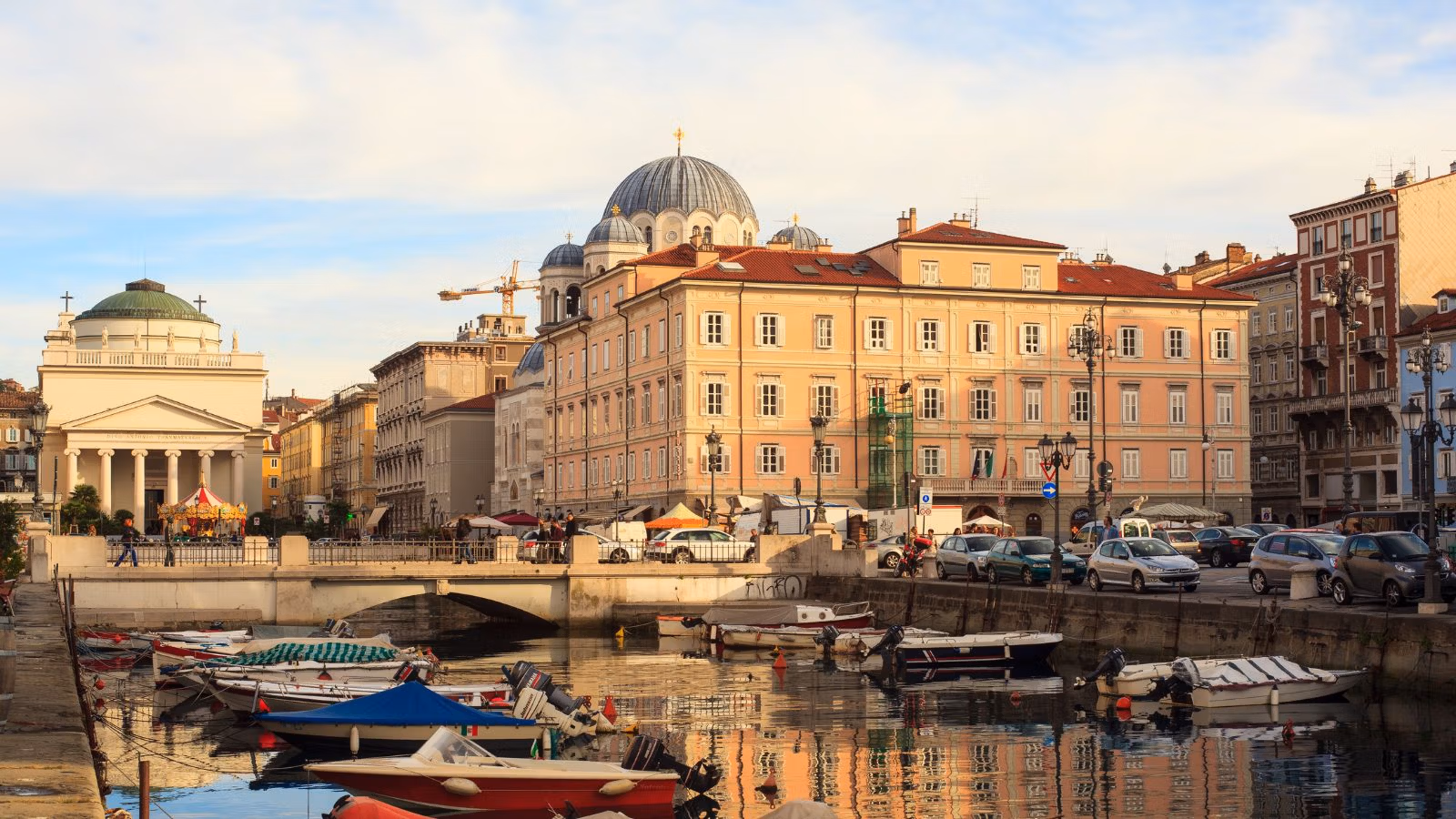 Waterfront city with historic buildings, boats and street activity.