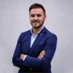 Man in a blue suit with arms crossed.
