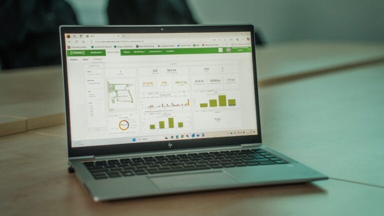 Laptop displaying a waste-management analytics dashboard for monitoring bin status and collection performance