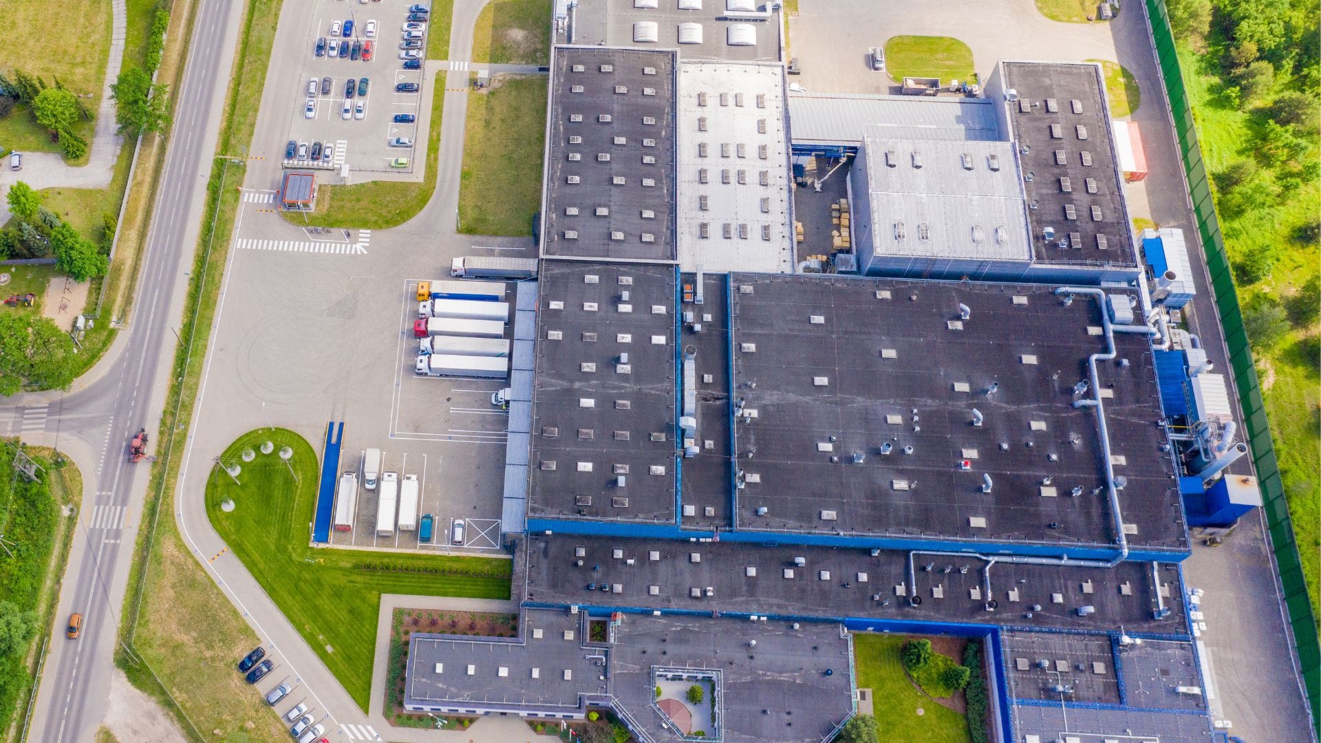 Aerial view of an industrial facility with trucks and parking areas.