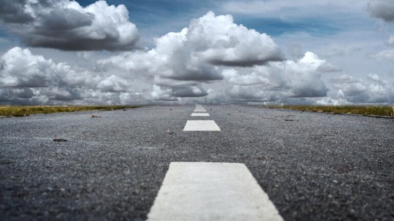 Empty straight road stretching into distant clouds.
