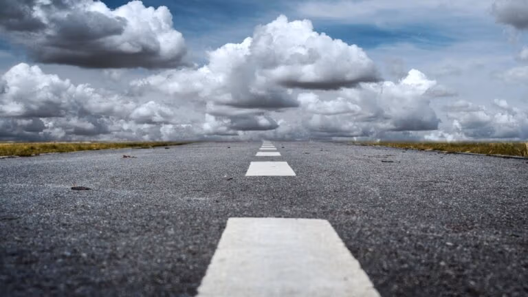 Empty straight road stretching into distant clouds.