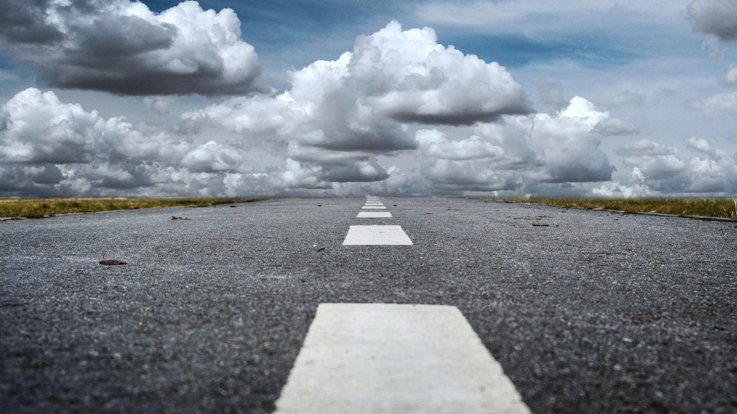 Empty straight road stretching into distant clouds.
