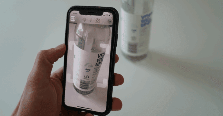 Person using a smartphone to scan a plastic bottle for recycling.