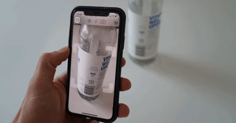 Person using a smartphone to scan a plastic bottle for recycling.