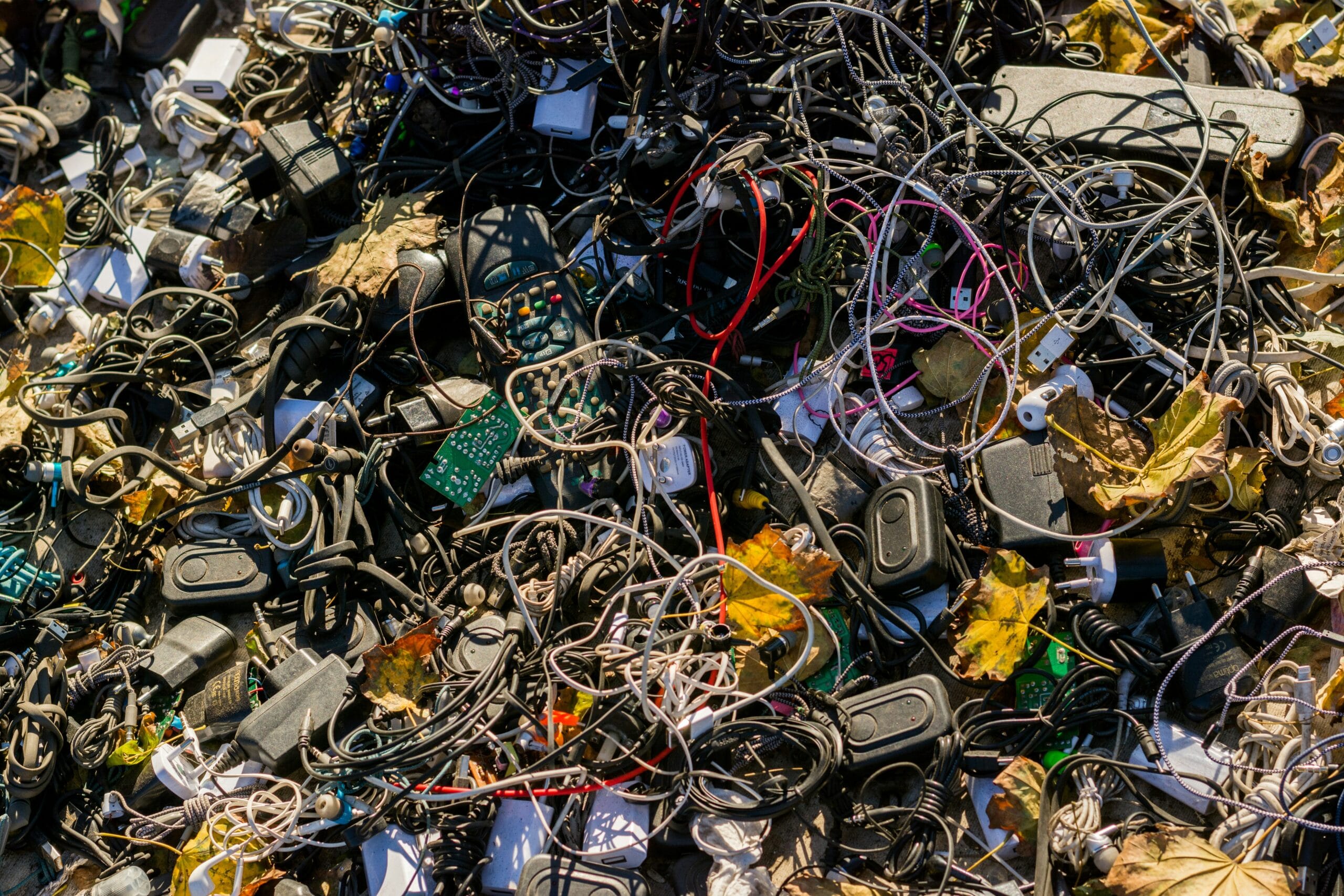 Pile of discarded electronic cables, chargers, and devices representing e-waste.