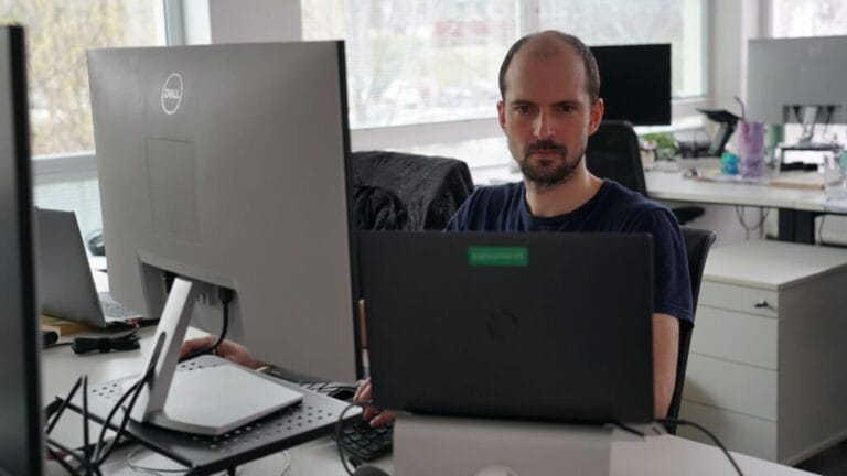 A person working at a desk with two monitors in a modern office environment.