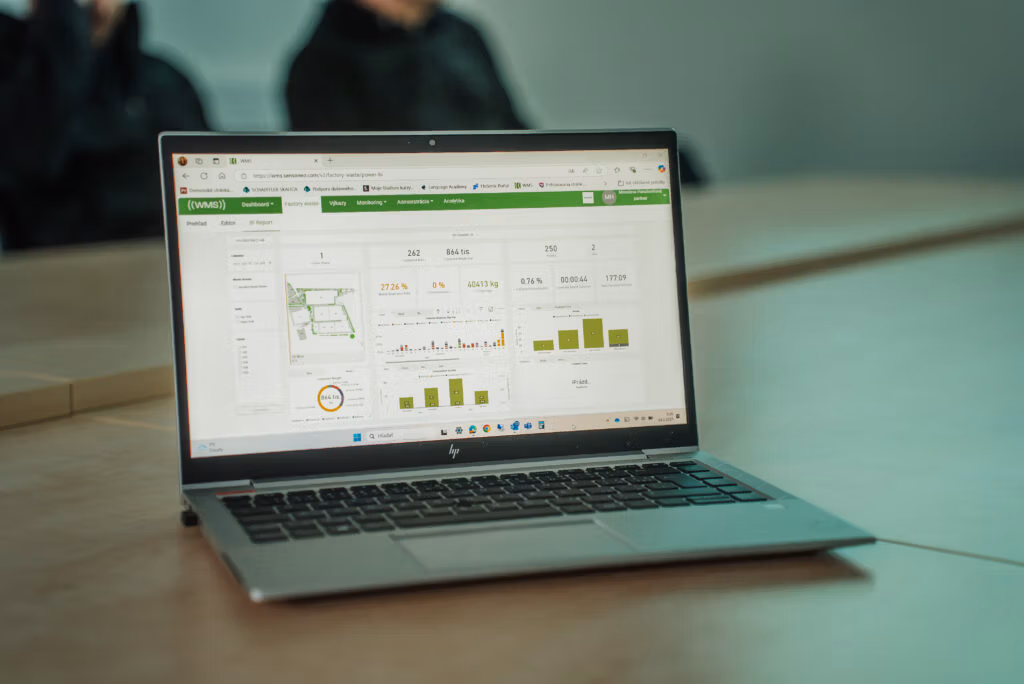 Laptop displaying a waste-management analytics dashboard with charts, metrics, and site overview map.