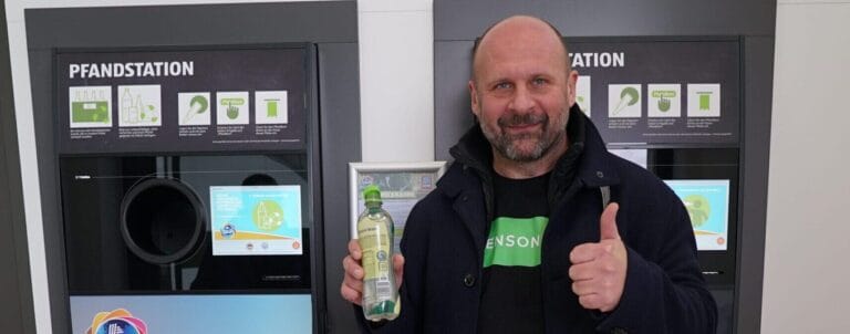Sensoneo CEO smiles while returning a bottle at a recycling station.
