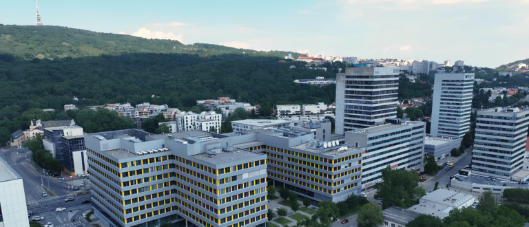 Aerial view of modern office buildings at the foot of a forested hill.